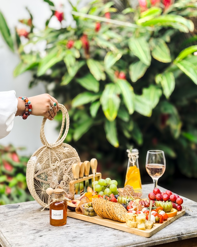 Tabla de quesos, frutas y detalles de la mesa en un jardín tropical